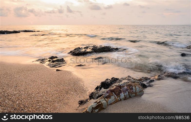 Sea sunrise cloudy sky with rocks on beach