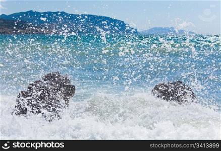 Sea surf wave break on coastline and Meganom cape on horizon right (Crimea, Ukraine)