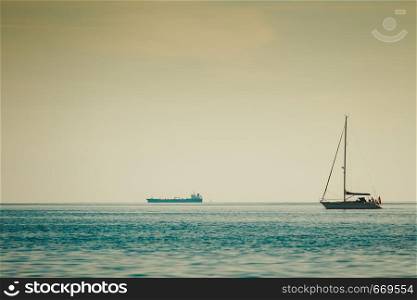 Sea transportation vehicles conept. Big industrial ship and small yacht on water horizon landscape. Big industrial ship and small yach on water landscape
