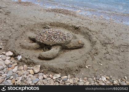 Sea turtle sand sculpture on sandy beach. Summer holidays.