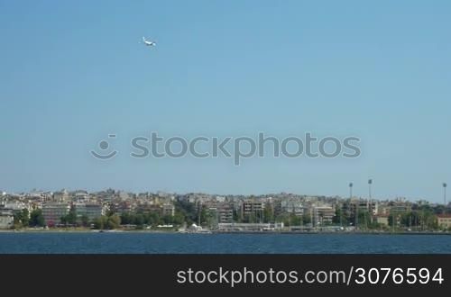 Sea view Thessaloniki, Greece. Visible from afar city with houses and in sky flying airplane