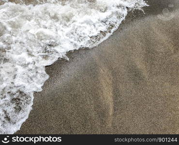 Sea wave on black sandy beach