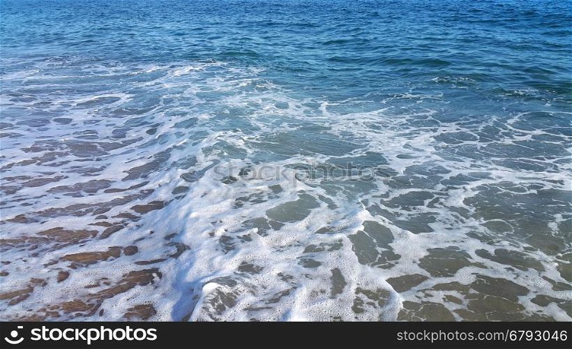 Sea wave with white foam on the beach, nature background