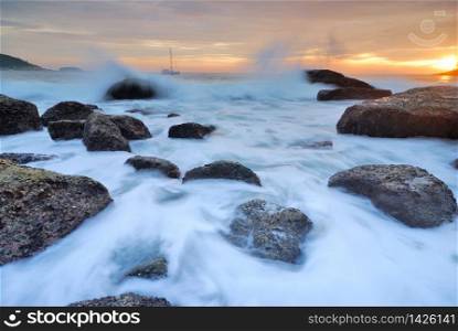 Sea waves lash line impact rock onthe beach