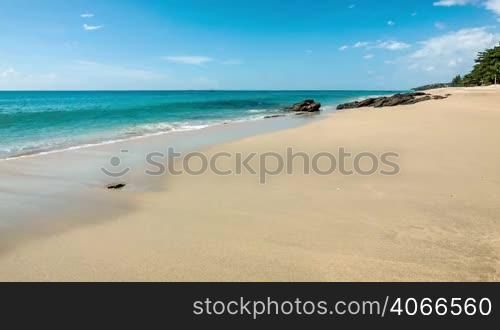 Sea waves on clear sand shore with rocks