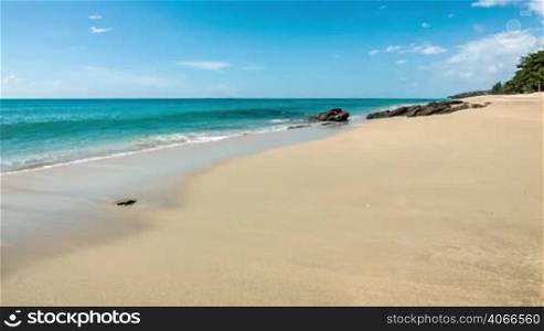Sea waves on clear sand shore with rocks