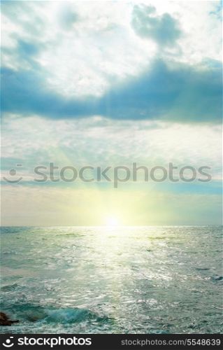 Sea, waves, sun and clouds. Sunset above the sea