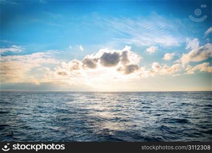 Sea with blue water, sky and clouds. Sunset above seascape