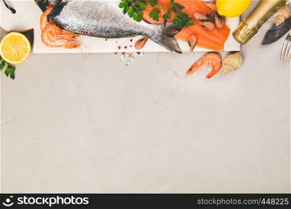 Seafood and wine on grey concrete background, top view, flat lay, copyspace. Salmon filet, sea bream, shrimps, snails, lemon shampagne. Seafood on grey concrete background, flat lay, top view