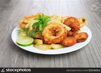Seafood dish with crumbed fish,calamari,prawn and potato chips on vintage table