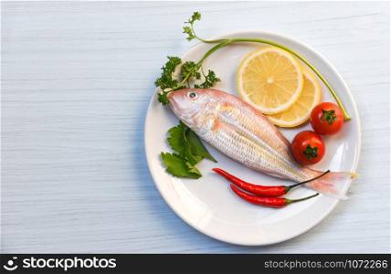 Seafood fish plate lemon parsley chilli and tomato on white plate table background top view