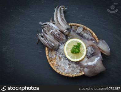 Seafood fresh squid on ice in basket with lemon parsley on dark background