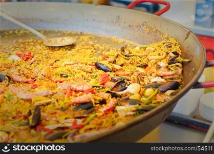 Seafood paella in a paella pan at a street food market Traditional Spanish paella with seafood and chicken.