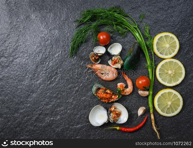 Seafood plate with shrimps prawns cooked shellfish mussel cockles boiled lemon herbs and spices on dark background