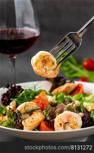Seafood salad and red wine on dark stone table