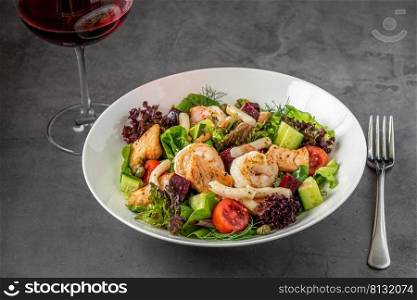Seafood salad and red wine on dark stone table