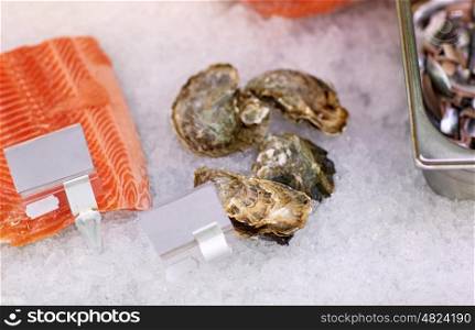seafood, sale and food concept - chilled fresh fish and oysters on ice at grocery stall