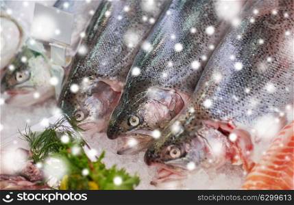 seafood, sale and food concept - chilled fresh fish on ice at grocery stall over snow. fresh fish on ice at grocery stall