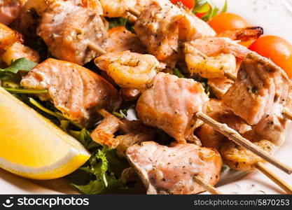 Seafood shashlik - slices of salmon and shrimps on a wooden skewers