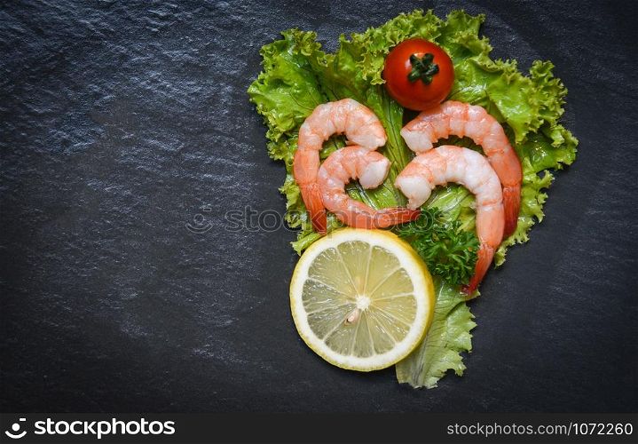 Seafood shrimps prawns boiled with tomato lemon and parsley in lettuce vegetable on dark background