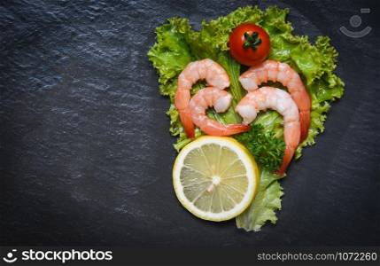 Seafood shrimps prawns boiled with tomato lemon and parsley in lettuce vegetable on dark background