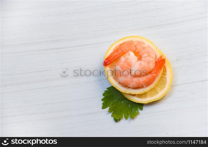 Seafood with shrimps prawns ocean gourmet dinner cooked with green parsley herb and shrimp on lemon on white wood background top view