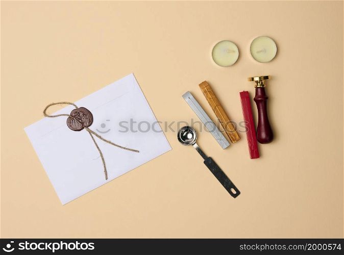 sealed white envelope with brown wax seal on beige background, flat lay