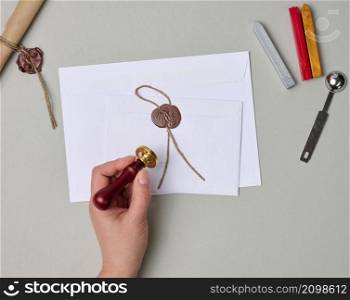 sealed white envelope with brown wax seal on beige background, flat lay