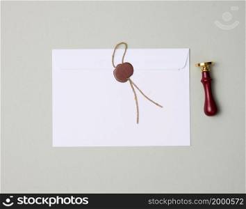 sealed white envelope with brown wax seal on gray background, flat lay
