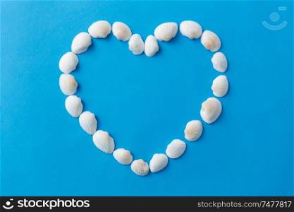 sealife, valentine&rsquo;s day, and summer concept - frame of white sea shells in shape of heart on blue background. sea shells in shape of heart on blue background