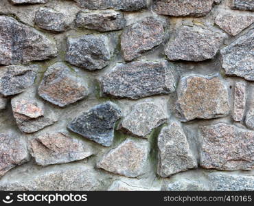 Seamless texture of a stone wall. Granite stone paving stone wall background. Abstract background of old stone cobblestone close-up.. Stone wall from a large granite cobblestone close-up