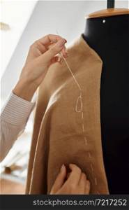 Seamstress hemming the dress on mannequin in workshop. Dressmaking occupation and professional sewing, handmade tailoring business, handicraft hobby. Seamstress hemming dress on mannequin, workshop
