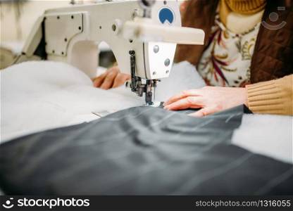 Seamstress sews fabrics on a sewing machine. Tailoring or dressmaking on clothing factory, needlework