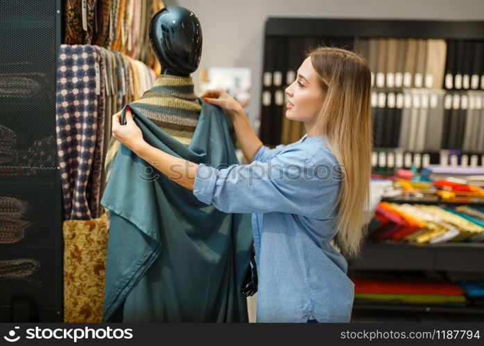 Seamstress with fabric at the mannequin in textile store. Woman choosing material for sewing, female tailor in shop, dressmaker. Seamstress with fabric at mannequin, textile store