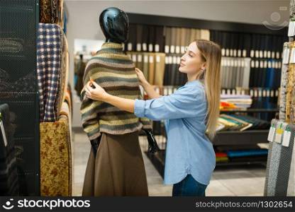 Seamstress with fabric at the mannequin in textile store. Woman choosing material for sewing, female tailor in shop, dressmaker. Seamstress with fabric at mannequin, textile store