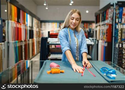 Seamstress with measuring tape and zipper, textile workshop. Woman works with cloth for sewing, female tailor at workplace, dressmaker. Seamstress with measuring tape, textile workshop