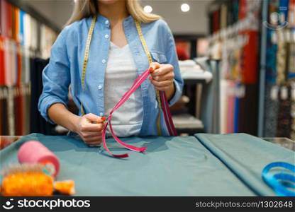 Seamstress with measuring tape and zipper, textile workshop. Woman works with cloth for sewing, female tailor at workplace, dressmaker. Seamstress with measuring tape, textile workshop