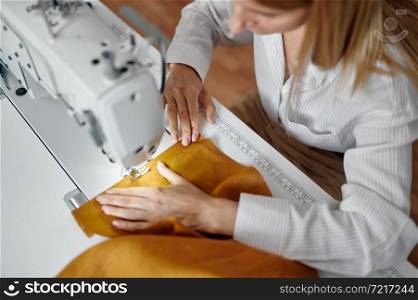 Seamstress works on sewing machine at her workplace in workshop. Dressmaking occupation, handmade tailoring business, handicraft hobby. Seamstress works on sewing machine at workplace
