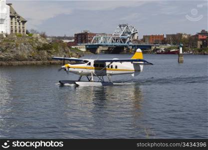 Seaplane taking off in Vancouver Islands harbor with blue bridge in background