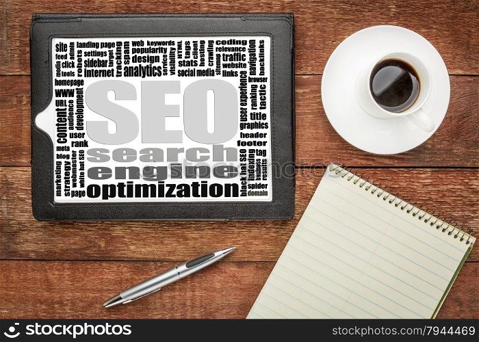 search engine optimization (SEO) word cloud on a digital tablet with coffee and notepad