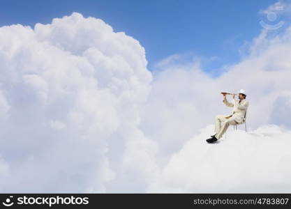 Searching for future perspectives. Businessman in white suit and hat sitting in chair and looking in spyglass