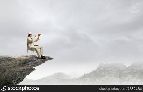 Searching for future perspectives. Businessman in white suit and hat sitting in chair and looking in spyglass