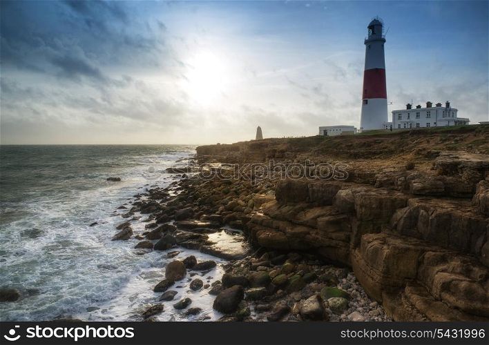 Seascape landscape of waves crashing onto rocks during beautiful Winter&rsquo;s day around lighthouse