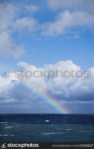 Seascape of the Pacific Ocean near Maui, Hawaii with rainbow and clouds.