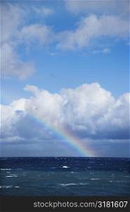 Seascape of the Pacific Ocean near Maui, Hawaii with rainbow and clouds.