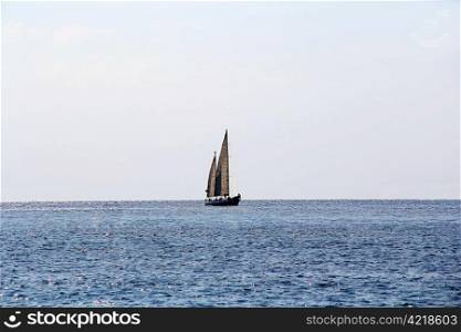 Seascape with calm water and sailboat in sunshines