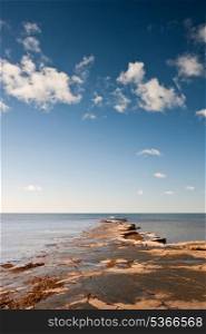 Seascape with Kimmeridgian rock ledges extending out to sea on blue sky day