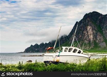 Seascape with old fishing boat on seashore and mountains in the background. Bleik village, Andoya island, Vesteralen archipelago.. Seascape with old fishing boat on shore