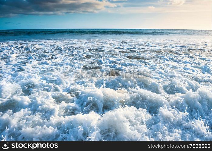Seascape with surf waves, bright sky and white clouds