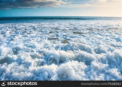 Seascape with surf waves, bright sky and white clouds